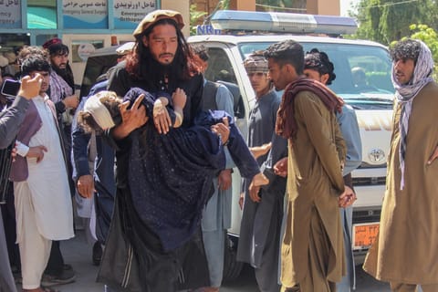 A man carries an injured girl to a hospital for treatment after a truck carrying Afghan families overturned in Jalalabad on May 30, 2026.