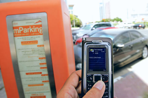 A motorist uses the mParking service by sending an SMSthrough his mobile phone at a paid parking zone on Sheikh Zayed road.