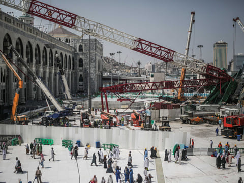 Muslim pilgrims walk past a collapsed crane that killed more than 100 people at the Grand Mosque in Mecca, Saudi Arabia