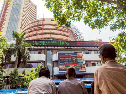 Men look at an electronic screen displaying stock figures at the Bombay Stock Exchange (BSE). As infections continue to surge, Indian investors are worried about the long term implications of COVID-19 on the economy