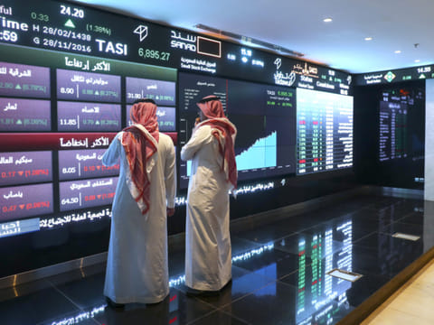 File picture used for illustrative purposes only. Visitors stand and watch stock movements displayed on large video screens inside the Saudi Stock Exchange.