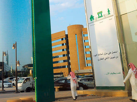 Saudi men walk in front of a branch of the ‘National Commercial Bank’ (NCB) in the capital Riyadh.