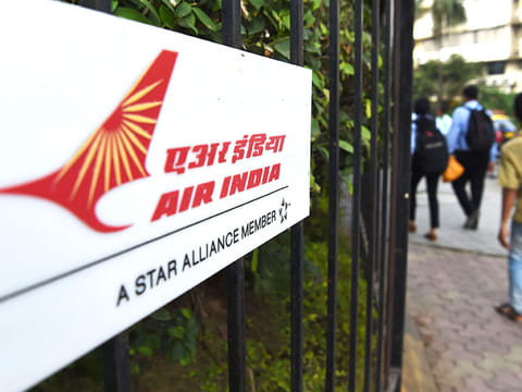 Pedestrians walk past a sign of state carrier Air India outside its headquarters in Mumbai. The building has been sealed for two days after an employee tested positive for COVID-19.