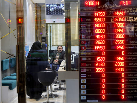Customers speak to a money exchange staff in downtown Tehran.