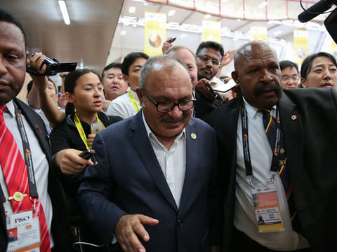 Papua New Guinea Prime Minister Peter O'Neill is escorted by security as he is chased by reporters after reading his statement at the end of the APEC 2018 summit at Port Moresby, Papua New Guinea on Sunday, Nov. 18, 2018.