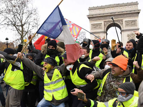Protestors wearing "yellow vest" (gilet jaune) gesture on December 8, 2018 near the Arc de Triomphe in Paris