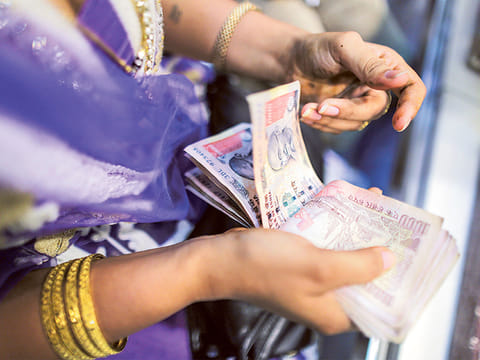 A customer counts Indian rupee banknotes at a jewellery store in Mumbai.