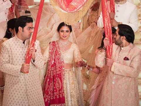 Industries chairman Mukesh Ambani's sons Akash (L) and Anant (R) taking part in a traditional marriage ritual of their sister Isha Ambani (C) to Indian businessman Ajay Piramal's son, Anand Piramal in Mumbai