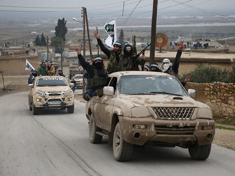 Turkish-backed Syrian fighters raise their weapons as they arrive in the border rebel-held town of Qirata after leaving their barracks in the town of Jarabulus on their way to the northern town of Manbij, on December 25, 2018.