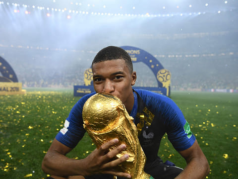 France forward Kylian Mbappe kisses the World Cup trophy.