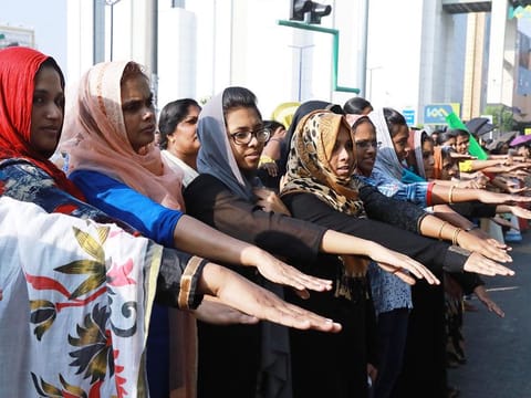 Women hold out their hands as they stand in a line to take part in a "women's wall" protest in Kochi, Kerala state on January 1, 2019.