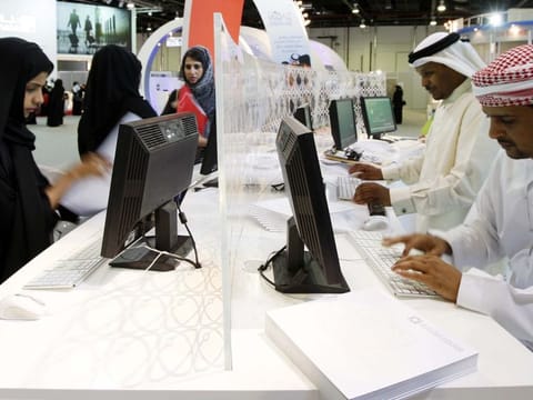 Emirati government employees are shown at work in a government office.