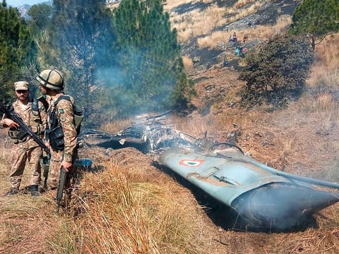 Pakistani soldiers stand next to what Pakistan says is the wreckage of an Indian fighter jet shot down in Pakistan controled Kashmir at Somani area in Bhimbar district near the Line of Control on February 27, 2019.