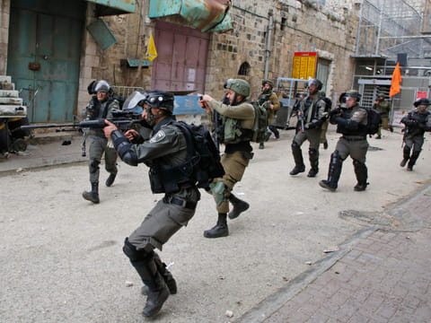 Israeli soldiers shoot rubber bullets at Palestinian protesters, near a gate leading to Hebron's main al-Shuhada street, closed by troops earlier in February, during an annual demonstration in memory of the 1994 Ibrahimi Mosque massacre, in the divided West Bank city of Hebron, on February 22, 2019.