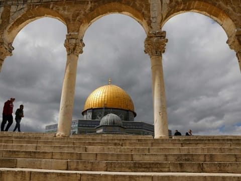 Palestinian Muslim worshippers walk past the Dome of the Rock mosque, situated in the Al Aqsa mosques compound.