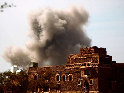 smoke billows behind a building following an air strike by the Saudi-led coalition in the Yemeni capital Sanaa
