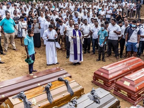 A priest officiates at a mass burial near St. Sebastian's Church in Negombo, Sri Lanka, on Wednesday, April 24, 2019.