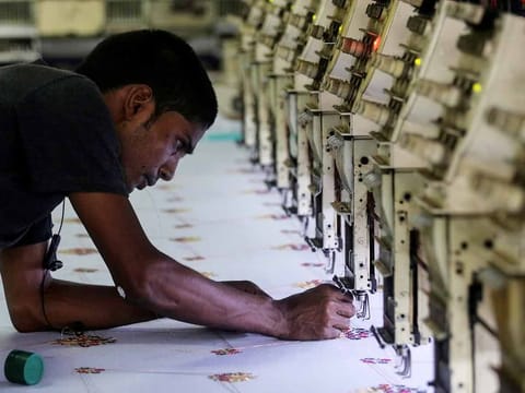 A worker adjusts the thread on an embroidery machine at a workshop in Mumbai, India, May 31, 2019.