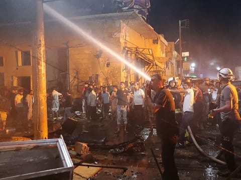 People try to extinguish a fire at the site of a car bomb blast in Azaz, Syria June 2, 2019.