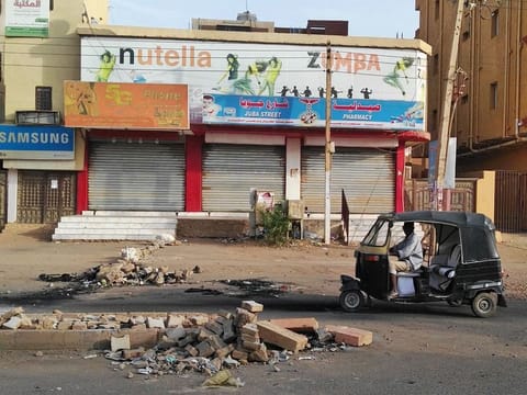 A Sudanese man drives his tuqtuq past closed shops in a residential neighbourhood of Sudan's capital Khartoum on June 4, 2019.