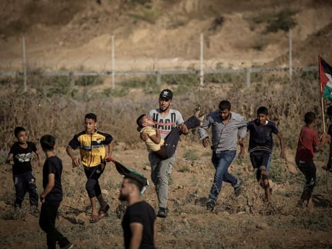Palestinians evacuate a wounded demonstrator during clashes with Israeli forces near the fence along the border with Israel near Bureij in the central Gaza Strip on June 14, 2019