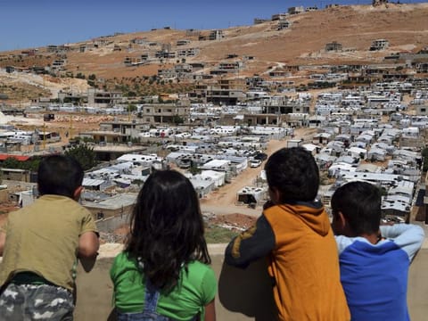 In this Sunday, June 16, 2019 photo, Lebanese children look from the rooftop of their home at a Syrian camp in the eastern Lebanese border town of Arsal, Lebanon.