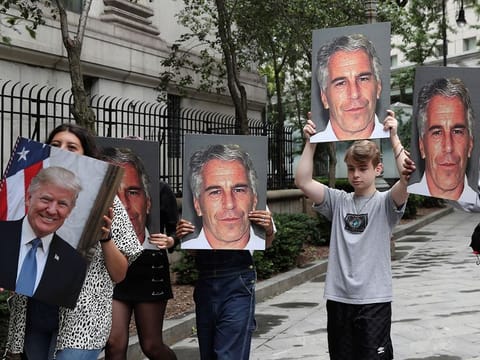Demonstrators hold signs aloft protesting Jeffrey Epstein, as he awaits arraignment in the Southern District of New York on charges of sex trafficking of minors and conspiracy to commit sex trafficking of minors, in New York, U.S.