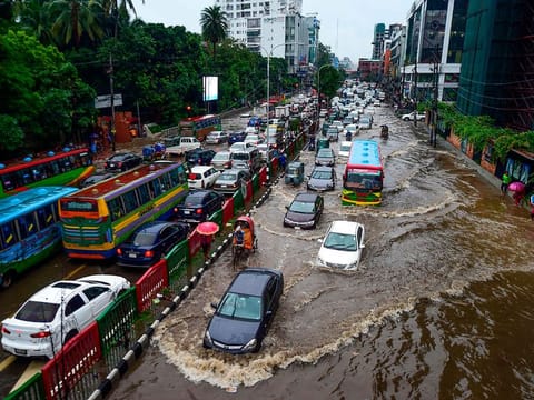 Bangladeshi drivers make their way through heavy rainfall at a water-logged street during the monsoon season in Dhaka.