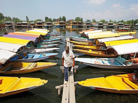 A boatman walks past the parked 'Shikaras' or boats for tourists on the banks of Dal Lake in Srinagar.