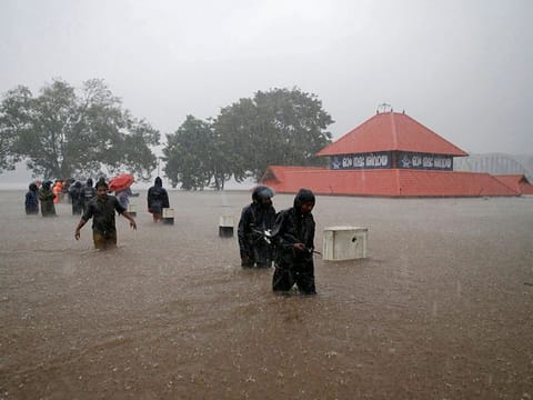 Members of a rescue team wade through a water-logged area past a submerged temple during heavy rains on the outskirts of Kochi in the southern state of Kerala, on August 8, 2019.