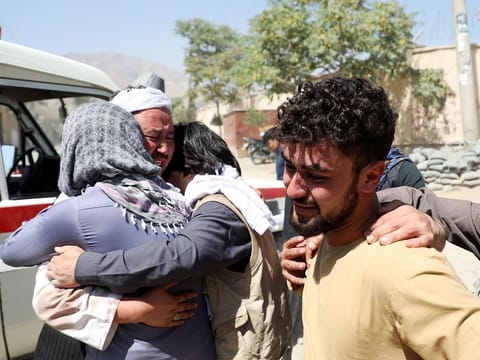Afghan men comfort each other as they mourn during the funeral of their relatives after a suicide bomb blast at a wedding in Kabul, on Sunday.