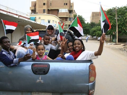Sudanese children wave small national flags as people celebrate outside the Friendship Hall in the capital Khartoum where generals and protest leaders signed a historic transitional constitution meant to pave the way for civilian rule in Sudan, on August 17, 2019.