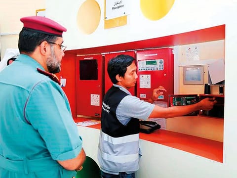 Civil Defence officials inspect fire alarm installation system at a building.