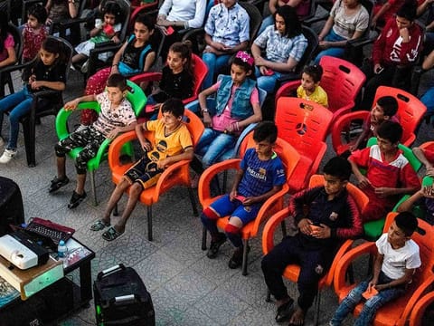 Children attend a film screening as part of the mobile cinema "Komina Film" initiative