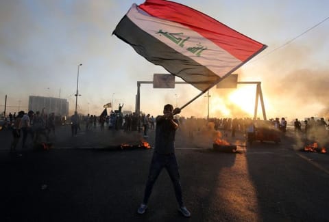 An Iraqi protester waves the national flag during a demonstration against state corruption, failing public services, and unemployment, in the Iraqi capital Baghdad on October 5, 2019.