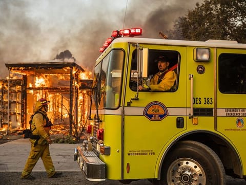 Firefighters survey a burning home along Highway 128 during the Kincade Fire in Healdsburg, California, U.S. on Sunday October 27, 2019.