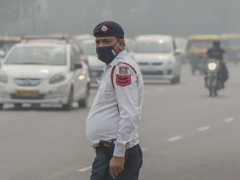A traffic policeman wearing an anti-pollution mask diverts traffic in New Delhi
