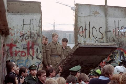 In this November 11, 1989 file photo, East German border guards are seen through a gap in the Berlin wall after demonstrators pulled down a segment of the wall at Brandenburg gate, Berlin.