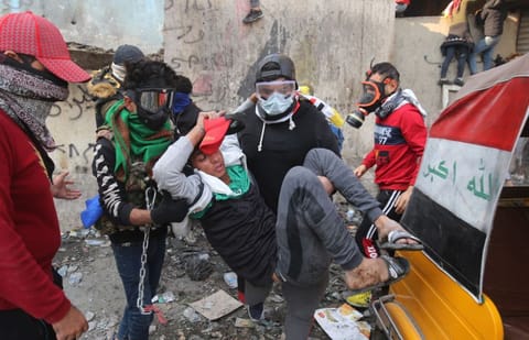 Iraqi demonstrators help an injured youth during clashes with security forces in Baghdad on Tuesday.