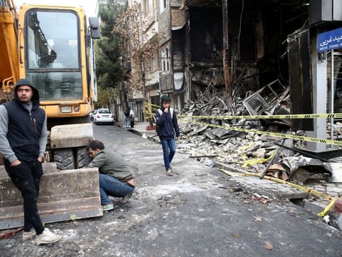 People walk near a burnt bank, after protests against increased fuel prices, in Tehran.