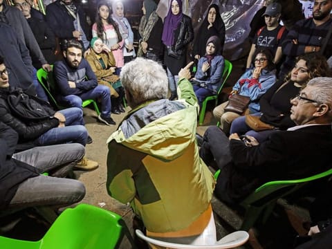 People gather at a tent where Lebanese anti-government protesters debate and discuss political and economic topics as part of an ongoing awareness at al-Nour Square in the northern port city of Tripoli on November 27, 2019.