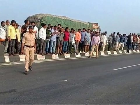 People gather at the site of the incident. The accused were killed when they allegedly tried to escape from the crime scene where the police had brought them to re-enact the incident.