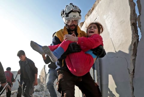 A member of the Syrian Civil Defence, also known as the White Helmets, carries a wounded girl after a team rescued her from the rubble of a building following a reported Russian air strike in the village of Tal Mardikh in Syria's northwestern Idlib province on December 19, 2019.