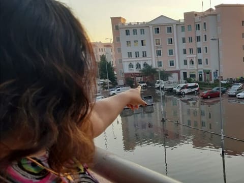 Asha Manoharan points to the car park in front of her building currently flooded in water