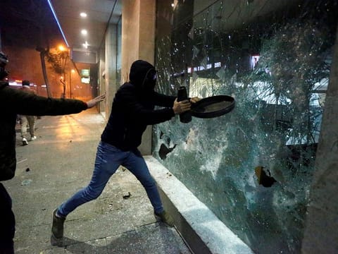 Protesters smash the window of a bank as demonstrations against the government continue in Beirut, Lebanon January 14, 2020.