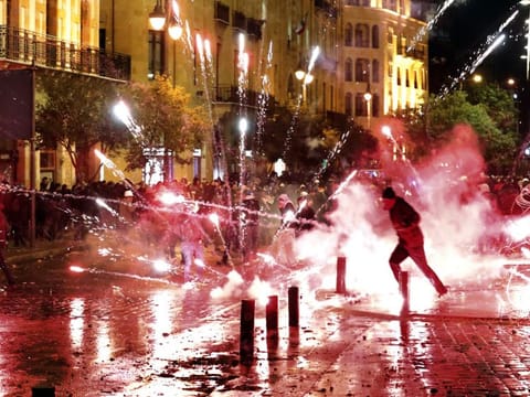 Lebanese protesters throw firecrackers at riot police during a demonstration against the new government, near Parliament Square, in Beirut on January 22, 2020.