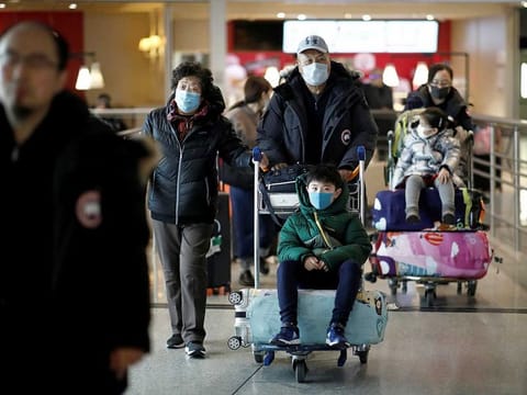 Passengers on an Air China flight from Beijing wear protective masks as they arrive at Charles de Gaulle airport in Paris. Airlines are cutting down their flights to and from China as the virus spread continues.