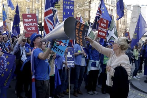 A supporter of Britain's departure from the European Union, at right, holds a placard up in front of supporters of remaining in the EU, including Stop Brexit Man, Steve Bray, with his foghorn, outside Parliament in London on February 27, 2019. Britain is finally due to leave the EU on January 31, 2020 after 47 years of membership.