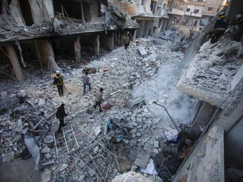 Members of the Syrian Civil Defence, also known as the White Helmets, search through the rubble and debris in a building at the site of reported airstrikes on the town of Ariha in the northern countryside of Syria's Idlib province on January 30, 2020.