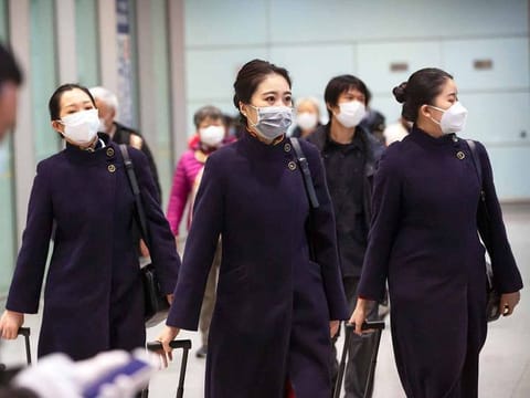 Flight crew members wearing face masks walk through the international arrivals area at Beijing Capital International Airport in Beijing. Asia’s loss of economic output due to the deadly coronavirus will likely persist until 2022, according to the International Monetary Fund.